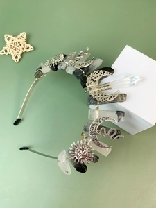 Macro detail of raw crystals and sun-moon silver charms on a celestial crown headband