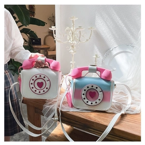 Close-up of novelty vintage telephone-shaped crossbody bags in white and gradient colors