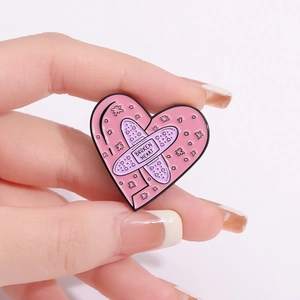 Macro shot of a pink heart badge featuring broken heart text and purple bandage detail