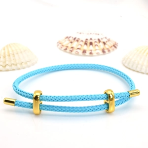 Detail view of blue adjustable woven bracelet with gold metal sliding clasp and shell accents