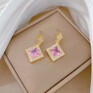 Close-up of pink square crystal earrings with pavé diamond halo on silk fabric