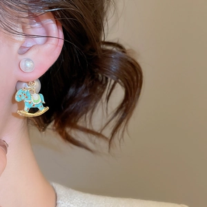 Detail of creative rocking horse pearl earring with blue enamel finish and gold edges