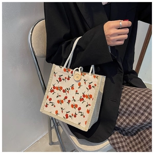 Detail of floral linen tote bag with woven rope handles and a round wooden button clasp