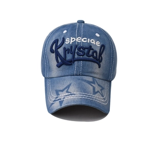 Macro shot of embroidered Krystal text and grey star on blue washed denim baseball cap