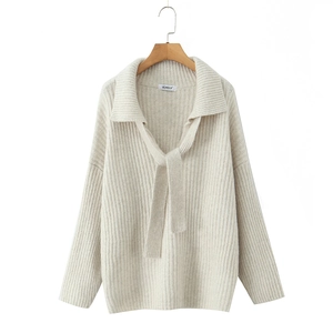 Detail eines beigen Strickpullovers mit Reverskragen und Schnürung am V-Ausschnitt