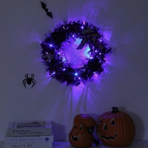 Halloween black rose wreath with purple LED lights and spider web on a dark wall