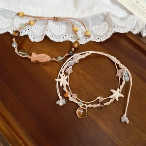 Detail von böhmischen Seestern- und Holzfisch-Anhängern mit Natursteinperlen auf Armbändern