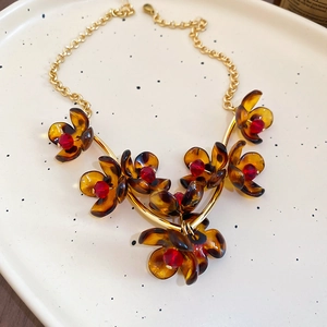 Detail of vintage leopard petal necklace with amber flower pendants and red beads