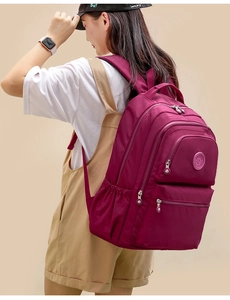 Detail view of purple nylon backpack featuring multiple zip pockets and a round logo patch