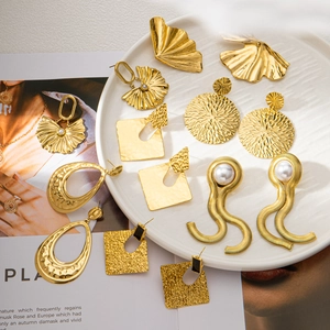 Various 18K gold-plated hoop earrings with fan and leaf designs displayed on a tray