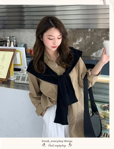 Detail of a chic black knitted scarf shawl paired with a brown shirt in a cafe setting