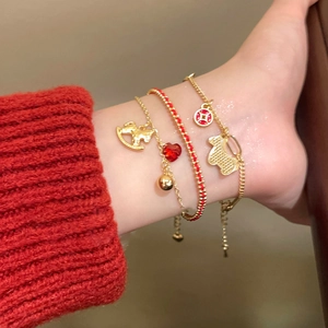 Close-up of three-piece gold and red cord charm bracelets with horse and heart pendants