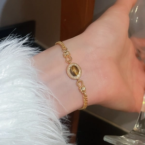 Gros plan du bracelet doré avec pierre œil de tigre ovale et cristaux pavés étincelants