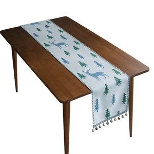 Modern chenille table runner with blue elk and pine tree patterns and decorative tassels