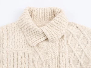 Detail eines groben Strickkragens an einem cremeweißen Herbst-Winter-Strickmantel