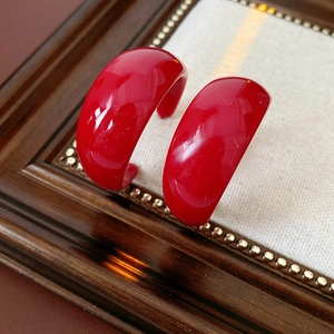 Detailed close-up of vibrant red resin C-shape hoop earrings on a vintage display