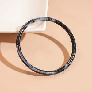 Macro detail of slim acrylic bangle with black and white marble ink texture effect
