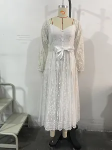 Détail de la robe en dentelle blanche avec col en V boutonné et élégant ruban en satin
