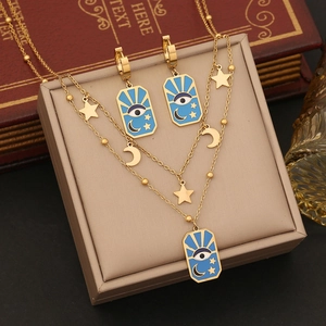 Golden double-layer necklace and earrings set featuring blue enamel evil eye and moon charms