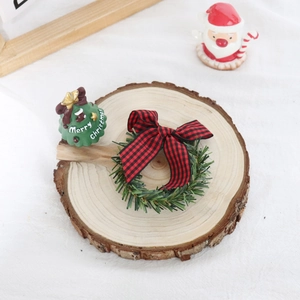 Close-up of Christmas pine needle napkin ring with bow and tree on wooden base