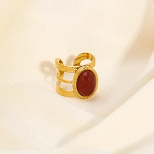 Detailed shot of a wide gold ring with an oval carnelian stone on silk fabric