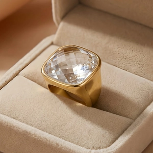 Detail of vintage gold wide band ring featuring a large faceted square crystal stone