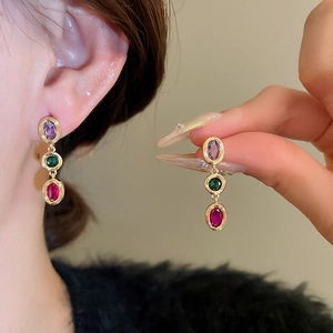 Detailed view of triple oval multi-colored zircon earrings with gold setting on model