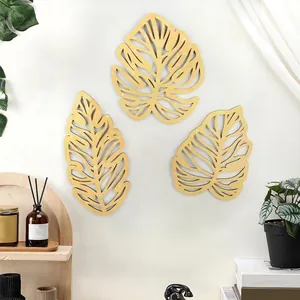 Detailed view of three tropical wooden palm leaf wall art pieces in a modern home interior