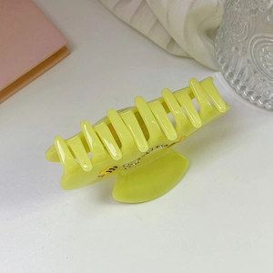 Close-up of yellow hair claw clip with floral patterns and sparkling rhinestones