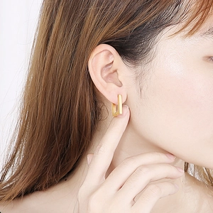 Minimalist gold rectangular geometric hoop earrings worn by model in a side view