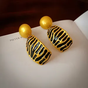 Vintage irregular golden ball earrings with black tiger pattern enamel on white book