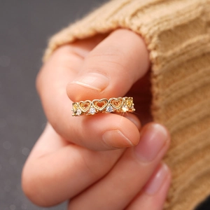 Macro shot of gold heart ring with cubic zirconia stones showing delicate hollow patterns