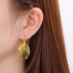 Gros plan de boucles d'oreilles dorées en U avec texture tissée creuse sur un mannequin