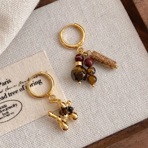 Detail of vintage gold plated earrings with tiger eye stone and metallic balloon dog charms