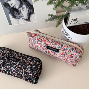 Close-up of floral corduroy pencil cases with zippers and minimalist brand labels