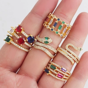 Detail view of colorful zircon snake ring and gold band sets on a hand model