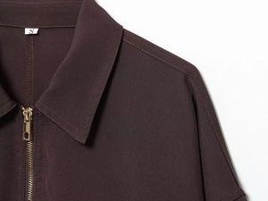 Détail de veste marron foncé montrant la fermeture éclair métallique et le col en sergé