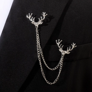 Détail d'une broche tête de cerf argentée avec chaînes sur le revers d'un costume noir