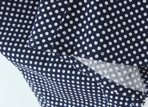 Macro detail of white polka dot print on navy blue fabric with high-quality stitching
