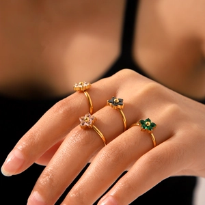 Detailed view of four golden flower rings with colorful zircon inlays on fingers