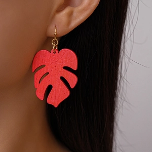Detail of leaf-shaped earring with intricate veins and gold hooks worn by a model