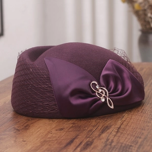 Detail of purple wool beret featuring a satin bow, rhinestone music note, and mesh veil
