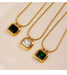 Primo piano di collane geometriche in oro con pietre color smeraldo, nere e bianche