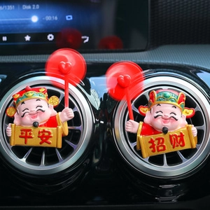 Close-up of God of Wealth car vent clip with rotating heart fan and red robes