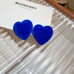 Close-up of heart-shaped blue flocked bear earrings on a white display card