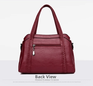 Detailed view of wine red leather handbag featuring woven decorative straps and zipper pocket