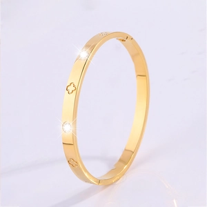 Detail view of gold titanium steel bangle with three hollow four-leaf clover cutouts
