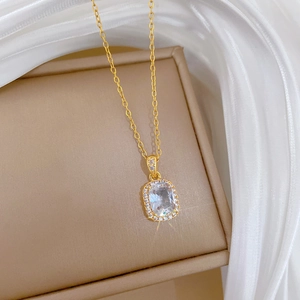 Macro shot of gold zircon square pendant on beige jewelry box with white silk