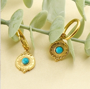 Close-up of gold stainless steel sunburst earrings with blue turquoise inlay center