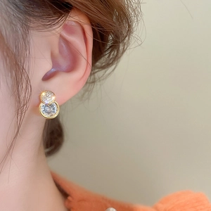 Close-up of elegant gold zircon double-ring earrings worn on model for luxury look